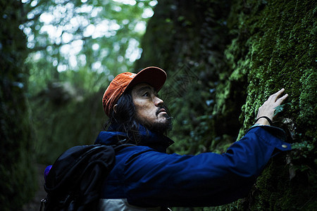 林中冒险旅行的男男背包客触摸石壁上的青苔图片