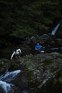 山林中旅行的两个男性在溪边休息图片