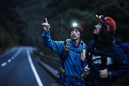 晚上走在森林旁公路上的男背包客图片