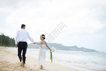 海滩边散步的新婚夫妇背影图片