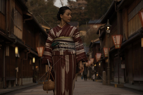 穿着和服的妇女走在光线昏暗的街头图片