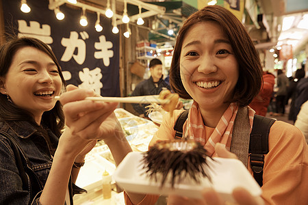 在日本旅行的女生在市集微笑吃东西图片