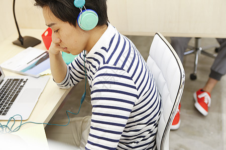 职场男性带着耳机在共享办公室工作图片