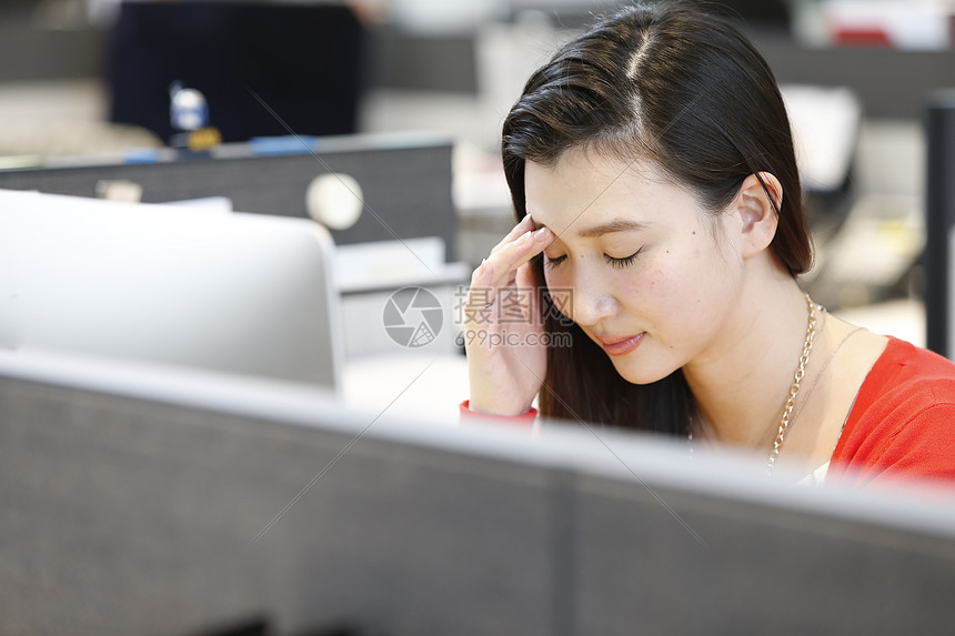 在电脑前按压眼部的职场女性图片