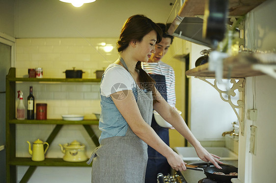 年轻夫妇在厨房带着围裙做饭图片