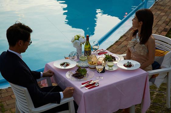 泳池边烛光晚餐的情侣图片