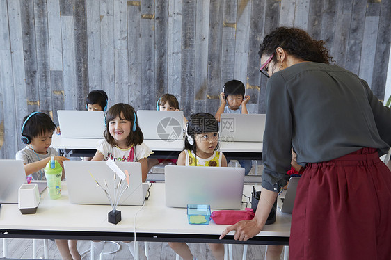 小朋友们带着耳机在笔记本上学习图片