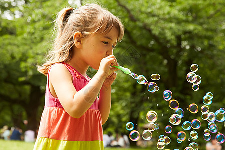 草地玩肥皂泡泡的小女孩图片