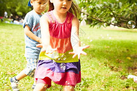 在公园草地上孩子们玩肥皂泡泡图片
