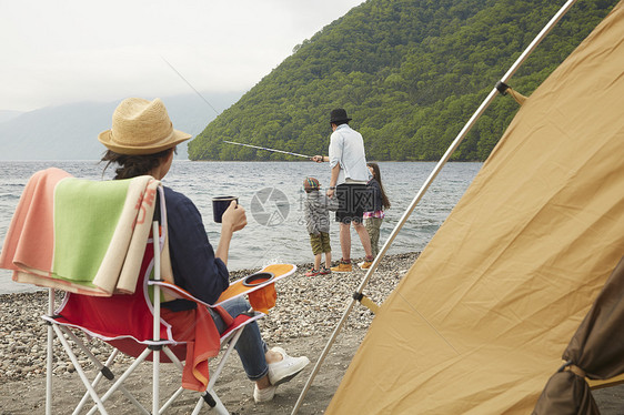 帐篷外坐在椅子上看钓鱼的女人图片