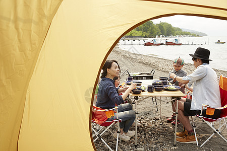露营区帐篷外吃烧烤的家庭图片