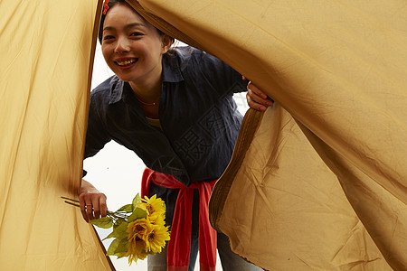 微笑掀开帐篷帘的拿着花束的女人图片