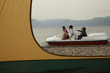 帐篷外湖上乘坐脚踏船游玩的四口家庭图片