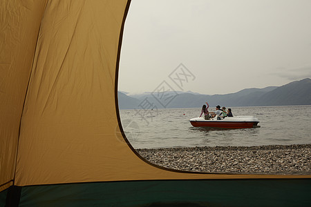 帐篷外坐脚踏船的四口之家图片