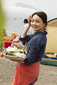 在海边准备露营端着食材的妇女图片