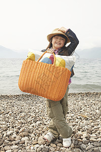 小女孩拿着野餐包在海边图片
