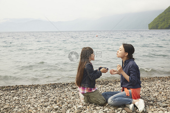 坐在湖边吃烧烤的母女图片