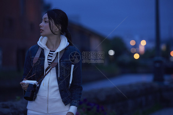 景点夜晚带着相机独自旅行的女生图片