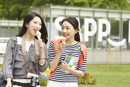 吃冰激凌带着相机旅行的2个女性图片