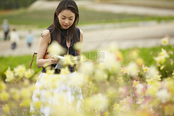 在花丛中拍摄鲜花的女孩图片