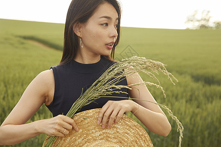 田地里手拿麦穗和草帽的女孩图片