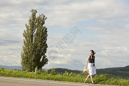 一个独自旅行的女人走在乡间道路上图片