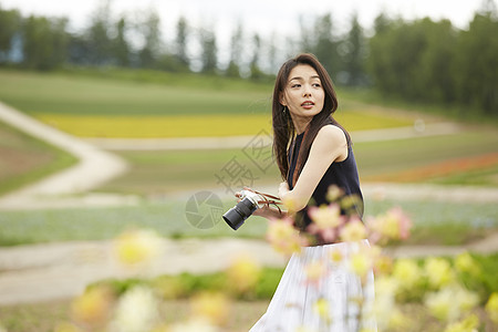 拿着相机散步在花卉丛中的女性图片