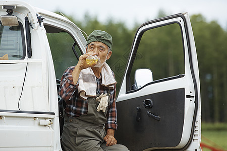 老人靠着农用轻卡休息喝水图片