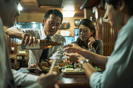 居酒屋内给好友倒酒的男士图片