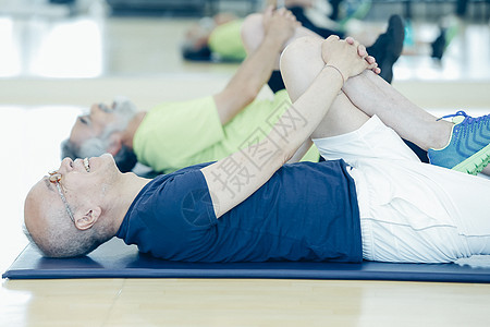 中年男人在瑜伽垫上做拉伸动作图片