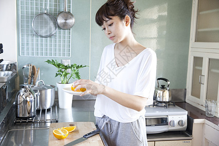 在厨房切橙子的女性图片