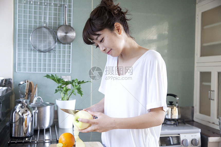 在厨房削苹果的女性图片