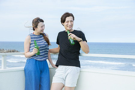 男女靠墙开心的喝啤酒图片