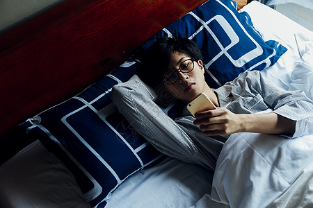 躺在床上玩手机的男性图片素材