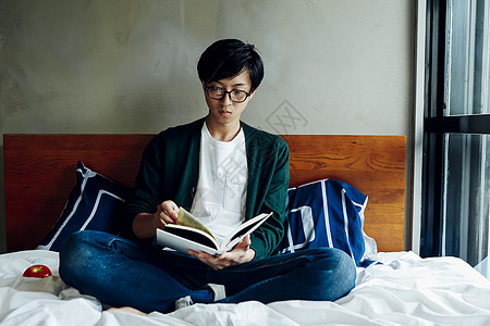 坐在床上看书的年轻男性图片