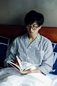 躺在床上看书的男子图片