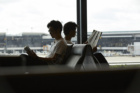 两个男人坐在候机厅看报纸图片