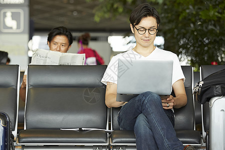 在机场候机厅拿着笔记本电脑工作的男性图片