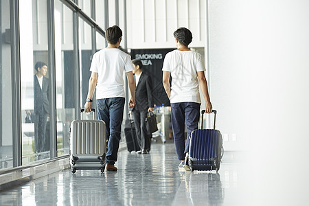 两个男子拖着行李走在机场大厅图片