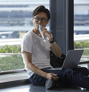 机场等待的男人喝水看电脑图片