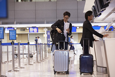 两个男人拖着行李箱在柜台登记图片