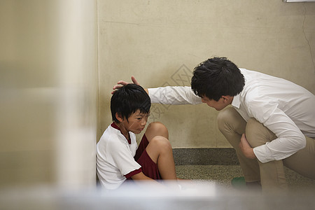 老师安慰缩在墙角的男学生图片