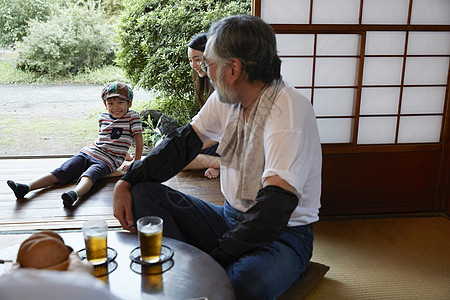 在夏日庭院里喝啤酒休息的一家人图片