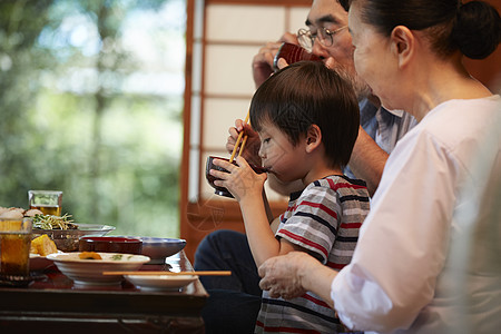 日式房屋餐桌边吃饭的3人图片