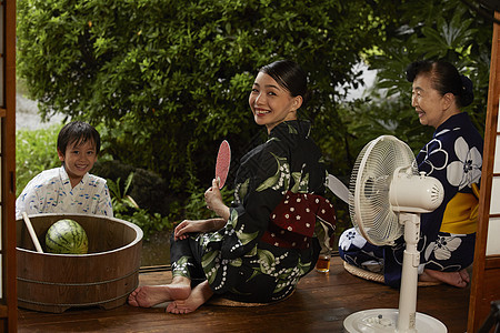 日式房屋中吃西瓜乘凉的3人图片