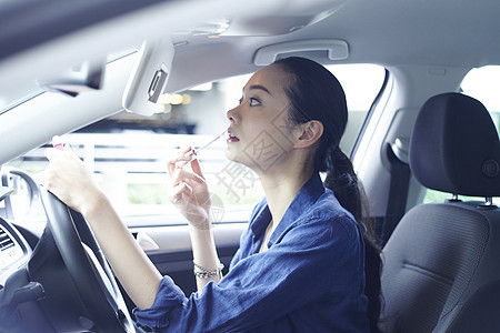 在汽车驾驶位上化妆的年轻女性图片