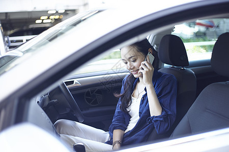 在汽车驾驶位上打电话的年轻女性图片