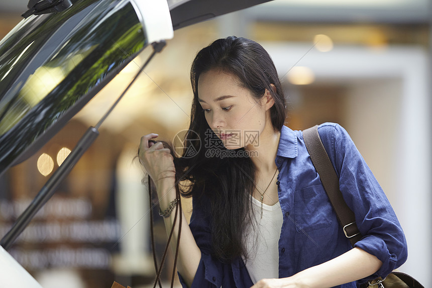 在街上把购物袋放入后备箱的女性图片