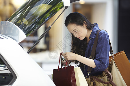 女孩把购买的商品放入后备箱图片