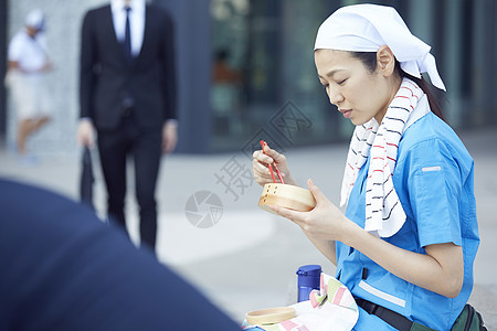 在办公楼下吃午餐的女清洁员图片